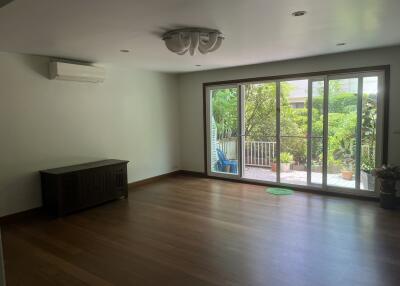 empty living room with wooden floor and sliding glass door leading to garden