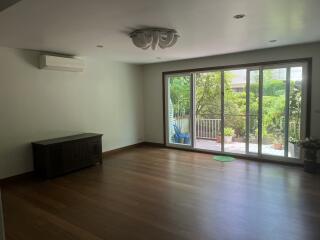 empty living room with wooden floor and sliding glass door leading to garden