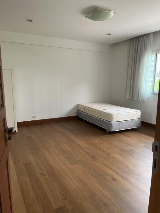 Spacious unfurnished bedroom with single mattress and hardwood floor.