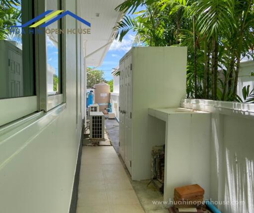 Outdoor utility space with air conditioning unit surrounded by greenery