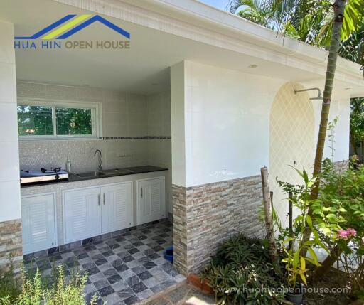 Outdoor kitchen with tiled floor and white cabinets