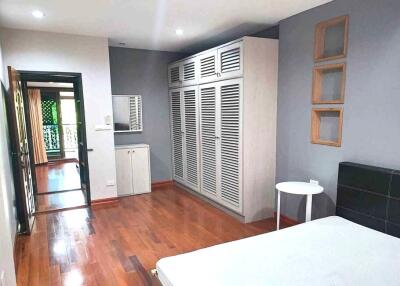 Spacious bedroom with wooden floor, large wardrobe and window offering natural light.