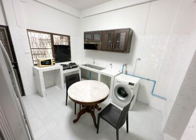 Kitchen with dining table, stove, sink, microwave, and washing machine