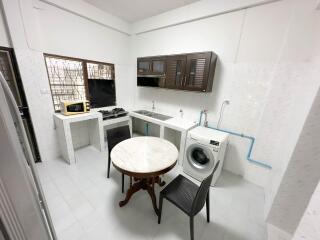 Kitchen with dining table, stove, sink, microwave, and washing machine