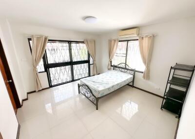 Bright bedroom with large windows, curtains, and minimalist furniture