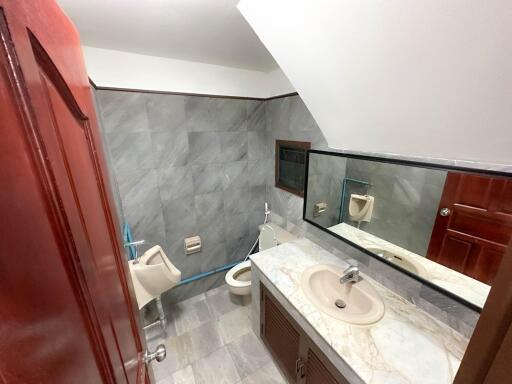 A bathroom with a marble sink, toilet, and urinal