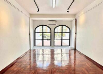 Spacious and bright living area with wooden flooring and large arched windows