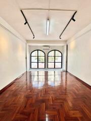 Spacious and bright living area with wooden flooring and large arched windows