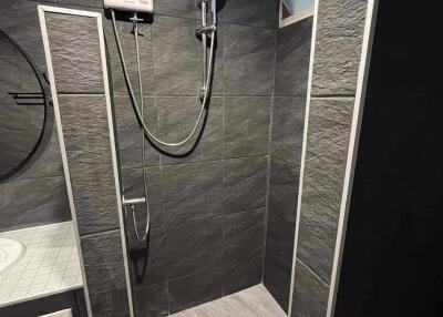 Bathroom with dark tiles and a modern shower setup