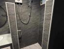 Bathroom with dark tiles and a modern shower setup