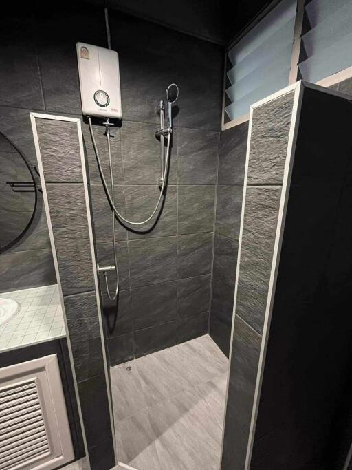 Bathroom with dark tiles and a modern shower setup