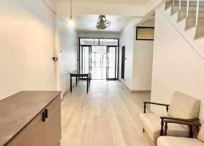 Minimalist living area with light wood flooring and staircase