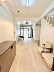 Minimalist living area with light wood flooring and staircase