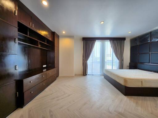 Spacious bedroom with large wooden built-in wardrobes and a bed