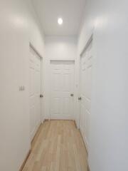 Hallway with three white doors and wooden flooring