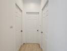 Hallway with three white doors and wooden flooring