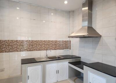 Modern kitchen with stainless steel range hood and black countertops