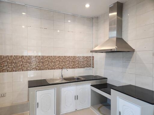 Modern kitchen with stainless steel range hood and black countertops