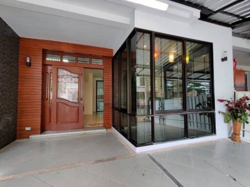 Modern house entrance with large wooden door and glass-enclosed porch