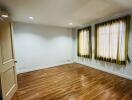 Empty bedroom with wooden flooring and two windows