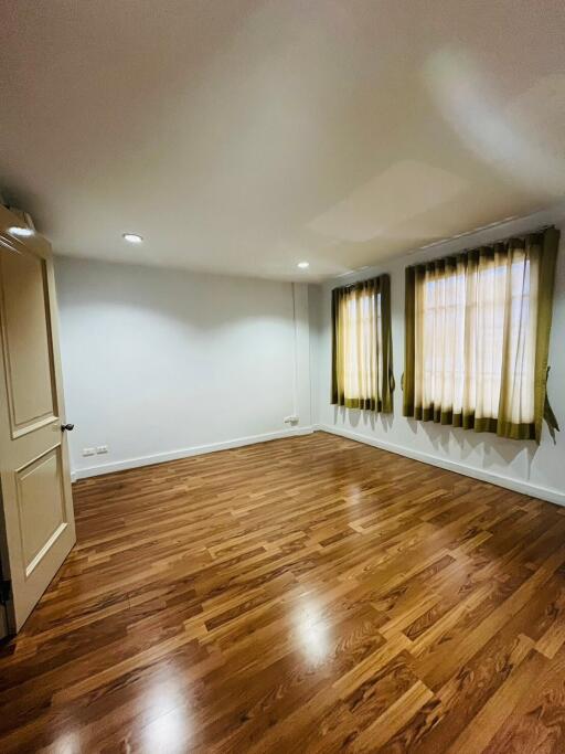 Empty bedroom with wooden flooring and two windows