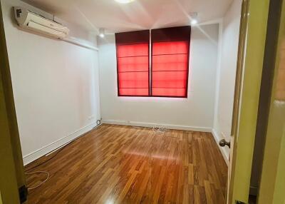 Bright bedroom with wooden flooring and red window blinds