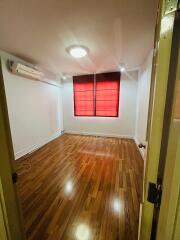 Bright bedroom with wooden flooring and red window blinds