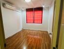 Bright bedroom with wooden flooring and red window blinds