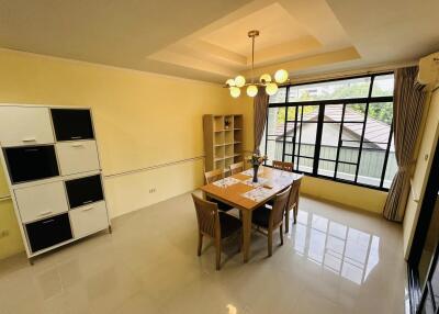 A well-lit dining area with a table set for four, large windows, and modern furnishings.