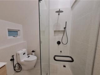 Modern bathroom with toilet, shower, and glass door