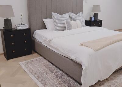 Modern bedroom with a neatly made bed, bedside tables, and lamps