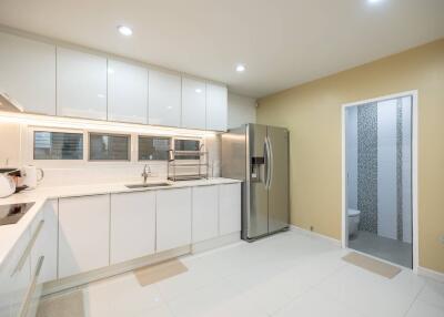 Modern white kitchen with stainless steel appliances and view into a bathroom