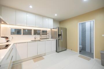 Modern white kitchen with stainless steel appliances and view into a bathroom