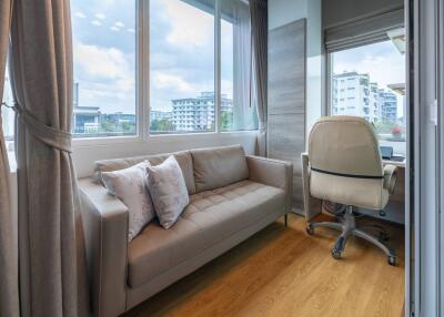 Bright living space with sofa and office chair by large windows