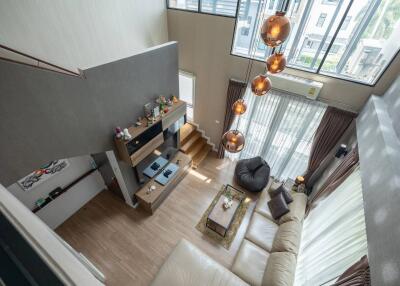 Contemporary high-ceiling living room with large windows and modern decor