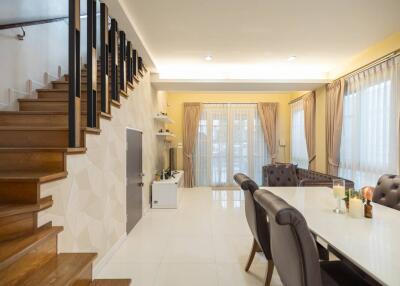 Modern living and dining area with elegant furniture and staircase