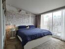 Modern bedroom with a large bed, brick accent wall, and floor-to-ceiling windows