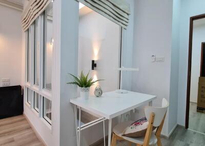 Well-lit home office with a desk, chair, wall-mounted light, and large windows