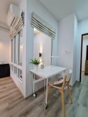 Well-lit home office with a desk, chair, wall-mounted light, and large windows