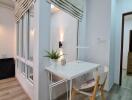 Well-lit home office with a desk, chair, wall-mounted light, and large windows