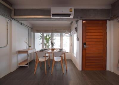 Modern dining area with wooden table and chairs, indoor plants, and large window