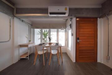 Modern dining area with wooden table and chairs, indoor plants, and large window