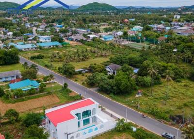 Aerial view of a residential area with a prominent white building with a red roof