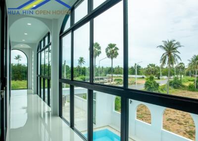 Hallway with large windows overlooking a pool and greenery