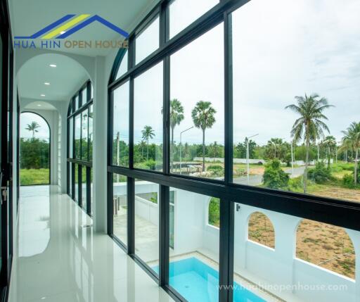 Hallway with large windows overlooking a pool and greenery