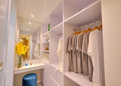 Modern walk-in closet with clothes hanging and vanity area