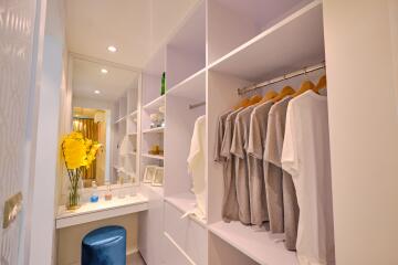 Modern walk-in closet with clothes hanging and vanity area