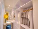 Modern walk-in closet with clothes hanging and vanity area