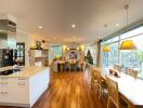 Spacious open-concept kitchen and dining area with hardwood flooring, large windows, and modern furnishings