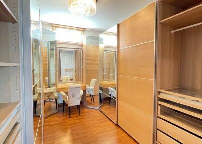 Spacious walk-in closet with wooden flooring and seating area